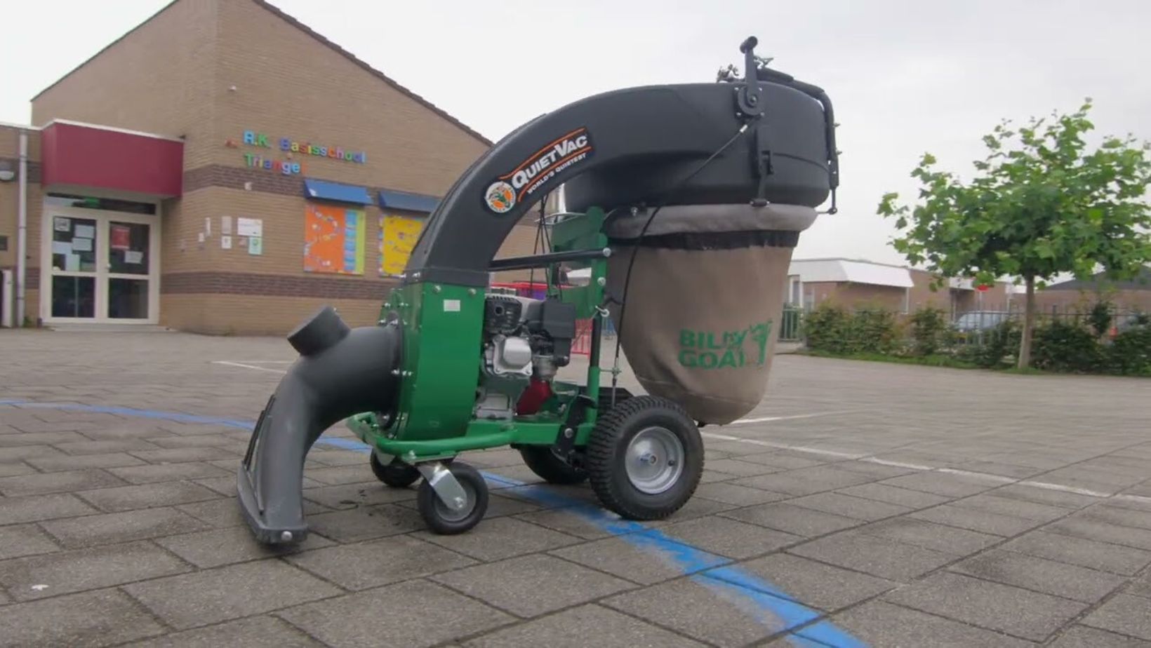 The Billy Goat QUIETVAC Petrol Industrial Vacuum clearing litter from outside a building.