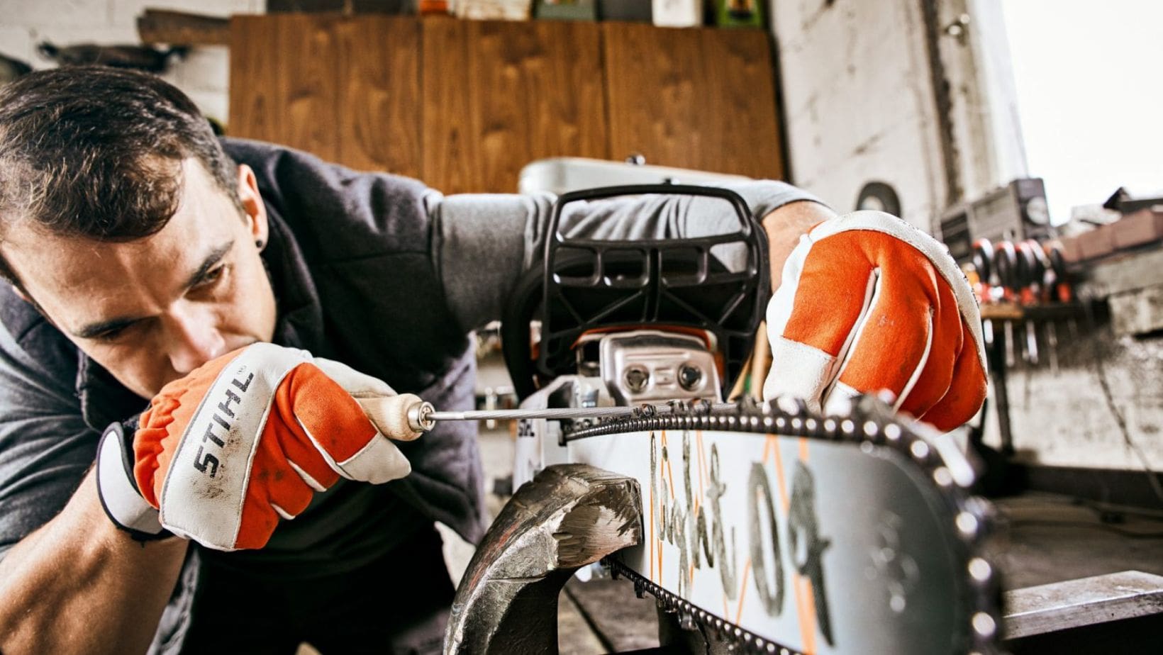 a man sharpening a chainsaw's teeth using a round chainsaw file