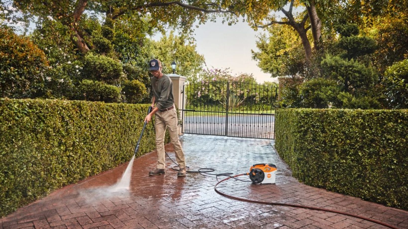 a man cleaning his front driveway with a STIHL pressure washer